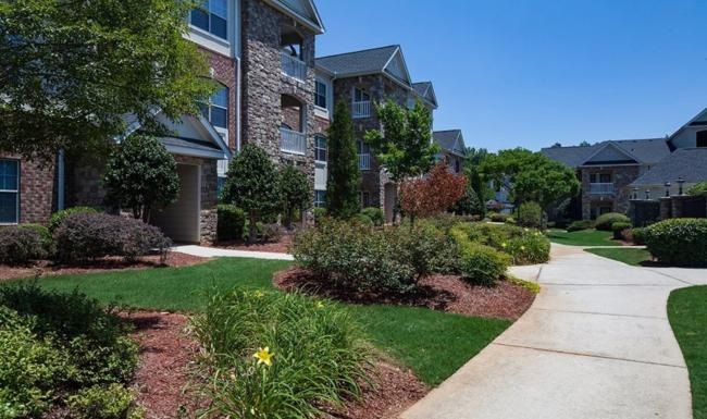 a sidewalk with bushes and trees in front of a building